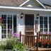 The Beach House in Mackinaw City, flower-filled porch with wooden railing and hanging baskets