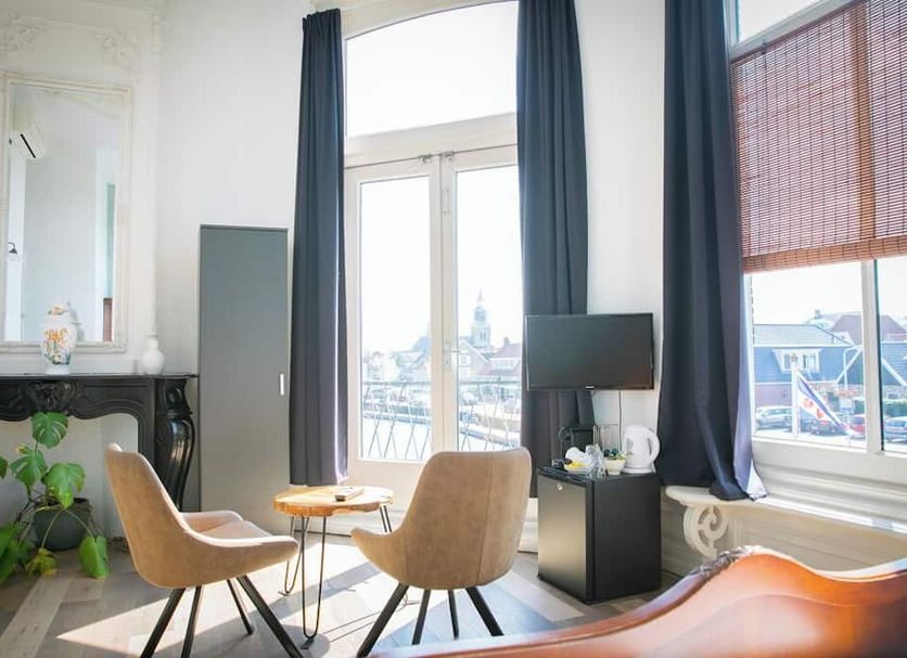 Boutique Hotel Joure room with large windows, city view, two chairs and small tables