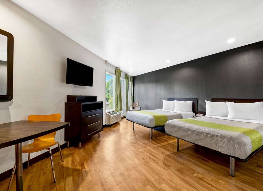 Studio 6 Portland OR guest room with two beds, wood floors, desk, TV, and window light