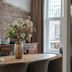 Hotel Het Oude Raadhuis dining room with brick accent wall, wooden table, and flower vase in Castricum