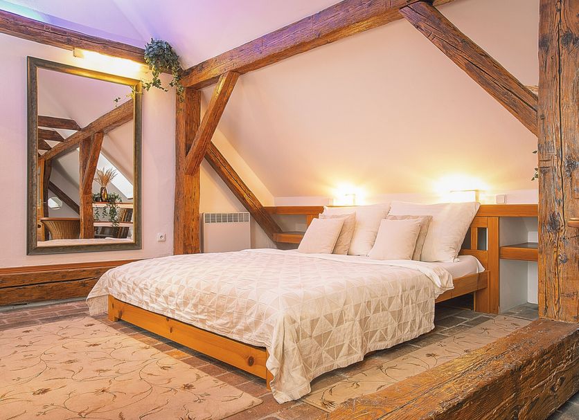 Wellness Pension Ametyst in Český Krumlov bedroom with exposed wooden beams and a large bed