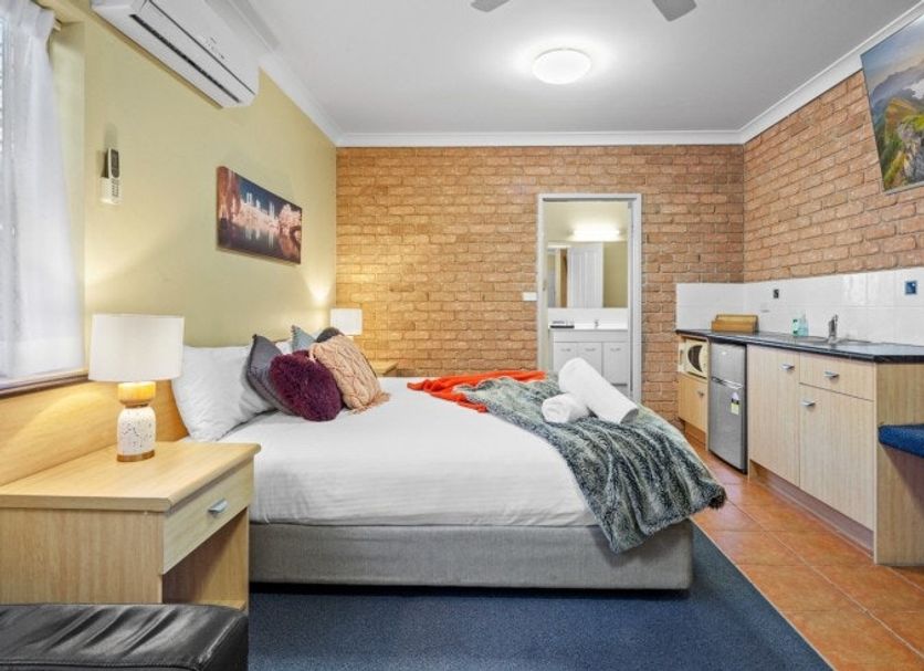 Park Beach Resort Motel room in Coffs Harbour with bed, kitchenette and brick accent wall