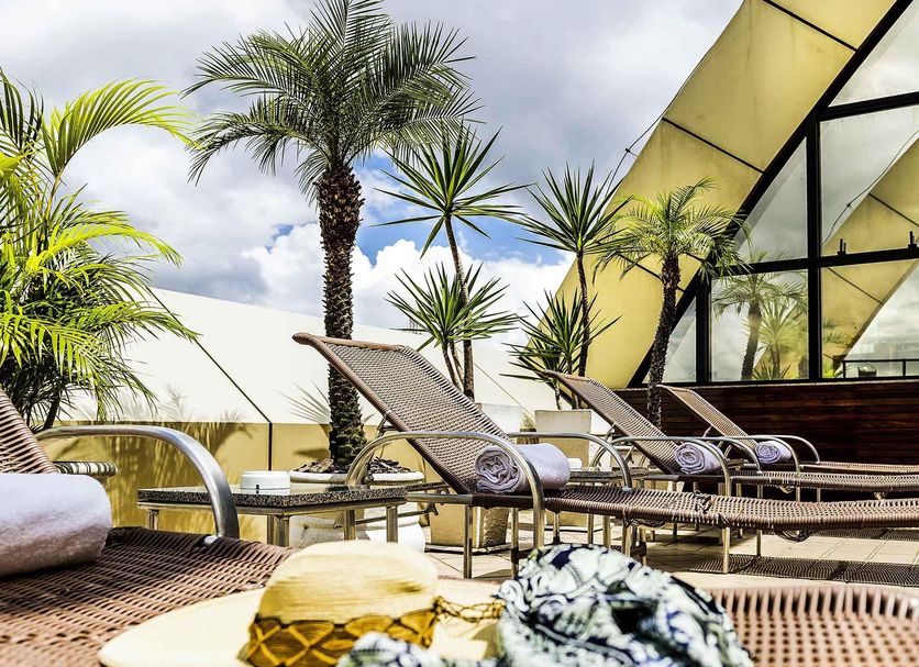 Grand Mercure Belém rooftop terrace with lounge chairs, palms and city views in Belém