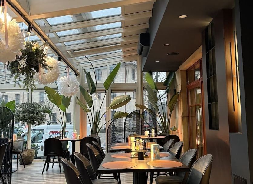 Hotel Arte in Brzeg dining area with tables, black chairs, skylight ceiling and indoor plants