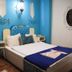 Elif Hatun Konagi Tarsus room with blue tufted headboard, white bed, and ornate wall decor