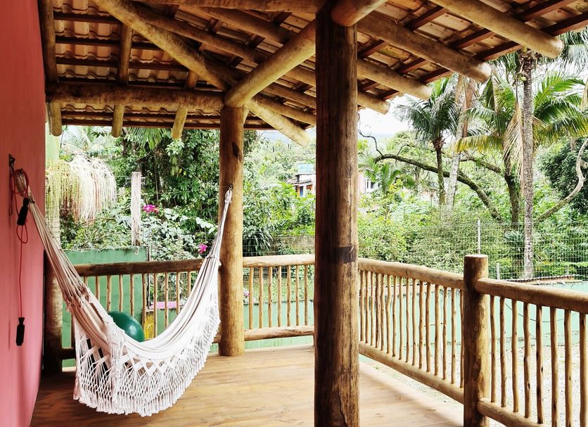 Pousada Tubes Maresias in São Sebastião with a hammock on a wooden porch overlooking tropical greenery.