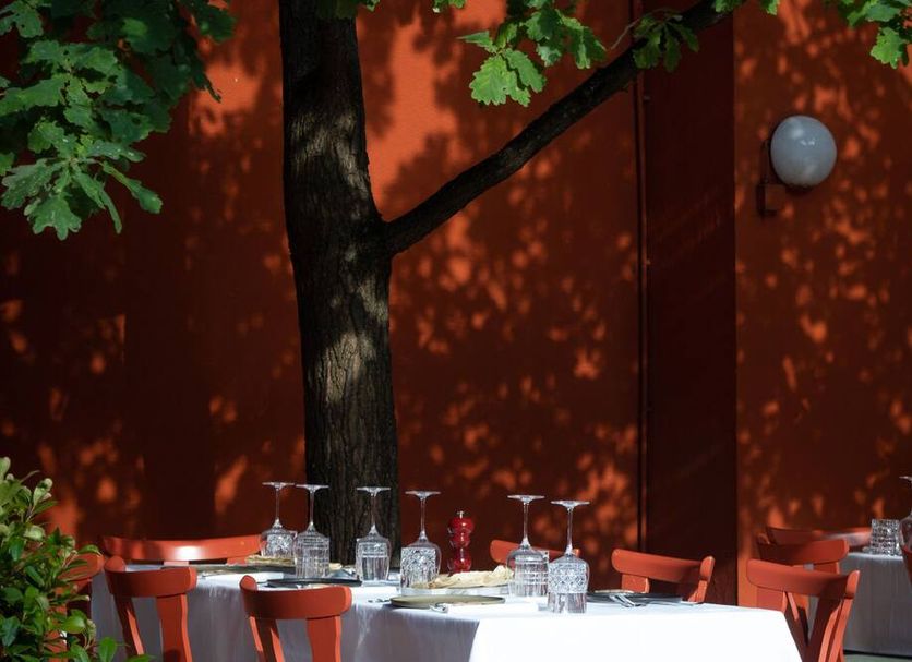 Weinstockwerk Hotel St Peter in Nuremberg outdoor terrace with red wall, trees, and set dining tables