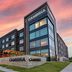 Cambria Hotel Austin Airport in Austin exterior at sunset with modern glass facade and covered entrance