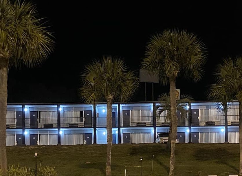 American Inn and Suites Jasper exterior at night with lit two-story rooms and palm trees