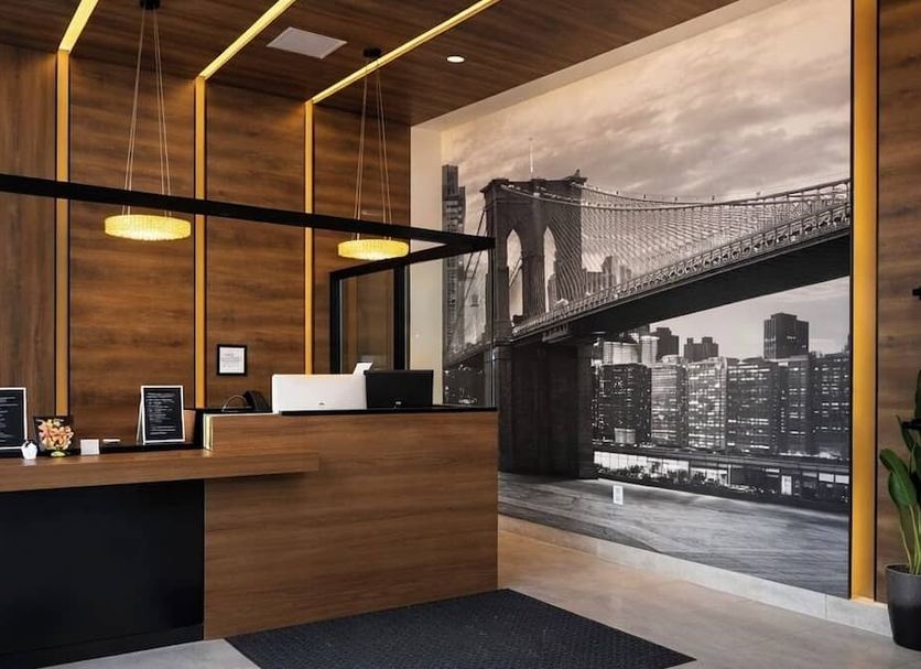Hotel Mirage Brooklyn lobby with wooden reception desk and black-and-white Brooklyn bridge wall mural