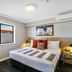 Potters Toowoomba Hotel guest room with king bed, bedside lamps, window, and air conditioner in Toowoomba