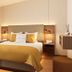 Galerie Hotel Bad Reichenhall bedroom with king bed, mustard bedding, bedside lamps and soft natural light