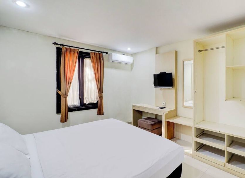 Dancenter Pondok Puri Ayu Denpasar guest room with bed, desk, TV and wall shelving
