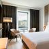 AC Hotels by Marriott Inverness guest room with king bed, chairs by window, and city view in Inverness