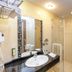 Colosseum Hotel in Mórahalom bathroom with sink, mirror, glass shower, and heated towel rack