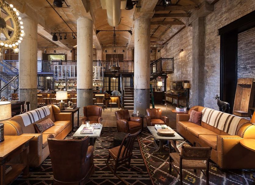 Hotel Emma in San Antonio lobby lounge with leather seating, industrial columns and warm lighting