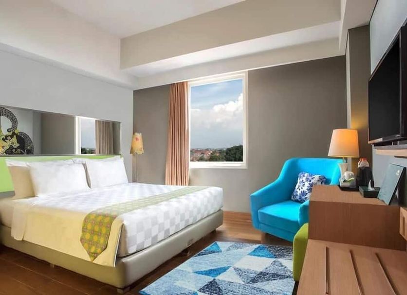 Khas Hotel Pekalongan room with bed, blue chair, TV, and city view in Pekalongan