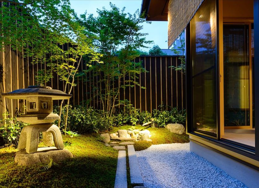 Luck You Kyoto courtyard with stone lantern, moss garden, and lit pathway beside guest room