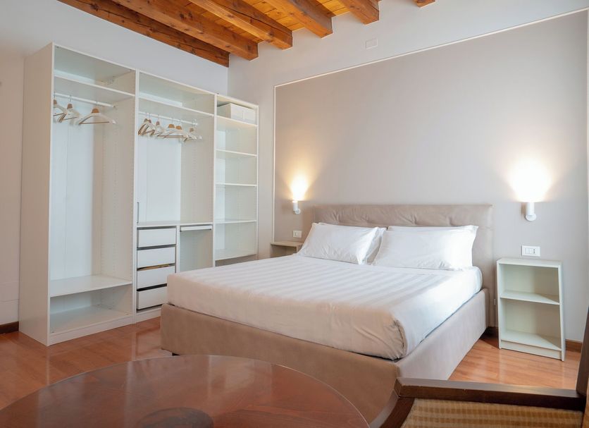 alla Corte Rossa Venice bedroom with wooden beam ceiling and open wardrobe