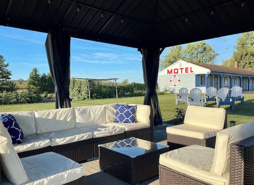 Best Motel Bowling Green outdoor seating area under a shaded cabana with white cushioned wicker furniture