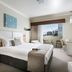 Grand Hotel and Apartments Townsville bedroom with king bed, desk, and balcony city view in Townsville