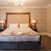 Dunadry Hotel And Gardens in Antrim bedroom with king bed, chandelier, patterned wallpaper and bedside lamps