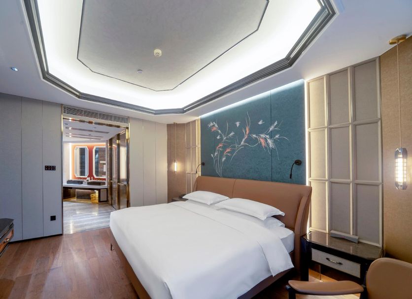 Shengshi Civil Aviation Hotel in Zhengzhou bedroom with king bed, geometric ceiling, and wall mural