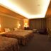 Hotel Sekia in Nankan guest room with three beds, warm lighting, and a lounge chair