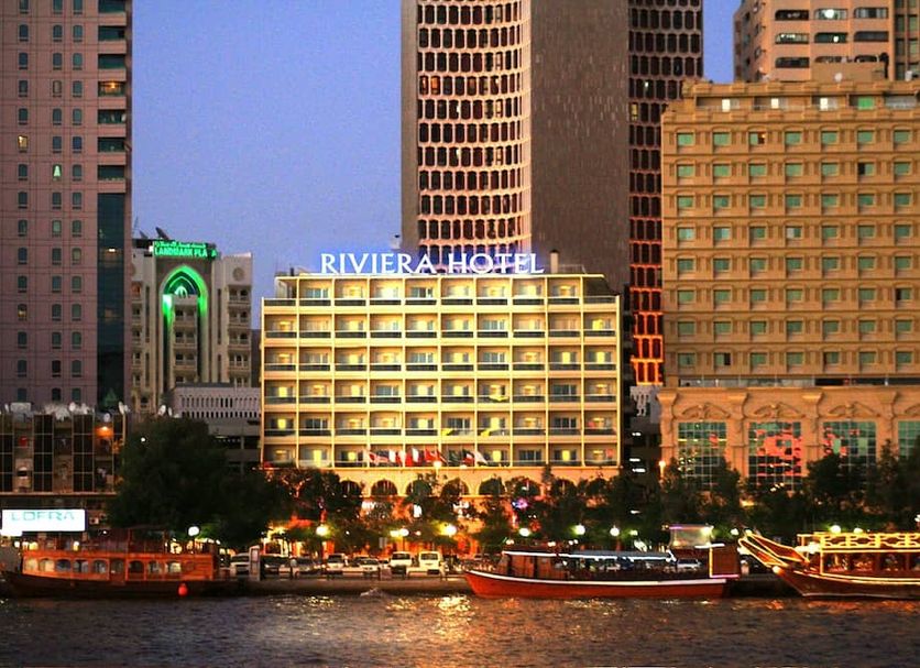 Riviera Hotel Dubai at dusk with illuminated facade on a waterfront skyline