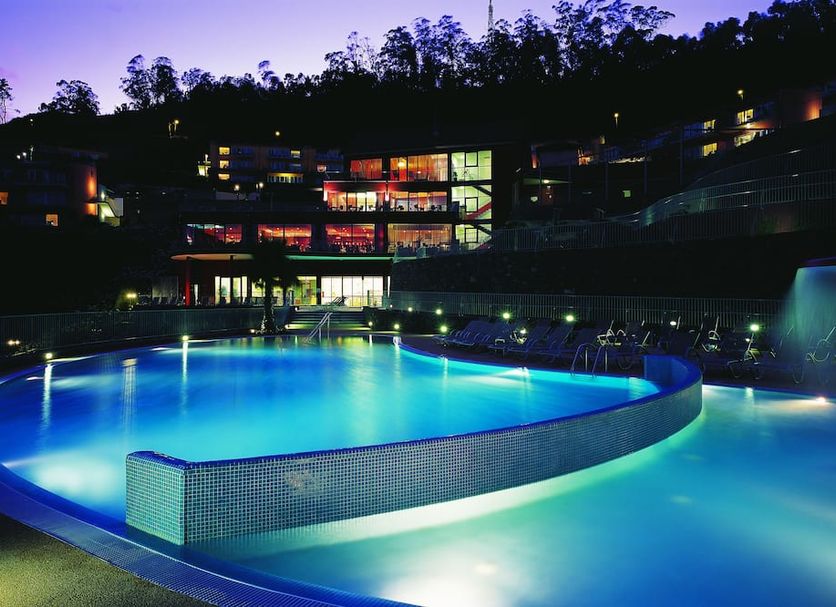 Village Cabo Girao in Câmara de Lobos with illuminated outdoor pool and resort buildings at dusk