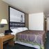 Super 8 by Wyndham Houghton Lake guest room with king bed, TV, desk, and lighthouse wall art