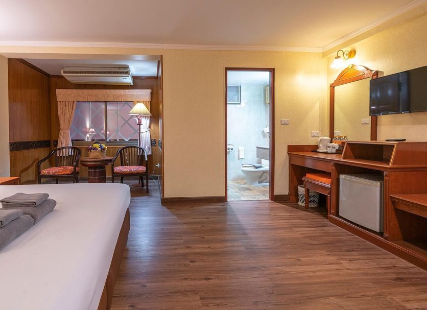 Sabai Inn Pattaya guest room with bed, dining nook, desk, and bathroom doorway