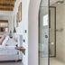 Pelican Bay Hotel in Platis Gialos: bedroom with king bed, wooden ceiling, and glass shower area