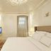 The Stay Galata Istanbul bedroom with ornate cream decor, king bed, wall-mounted TV, and sofa alcove