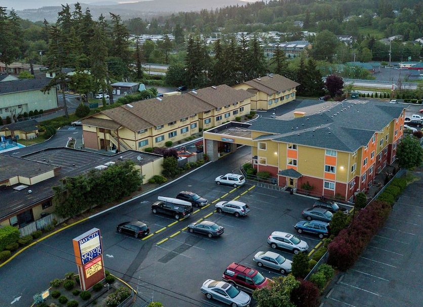 Bay City Motor Inn in Bellingham with a parking lot, colorful exterior, and surrounding trees