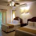 La Ensenada Beach Resort, Tela: twin-bed guest room with ceiling fan, wall sconce and curtained windows
