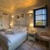 Castello Antico Hotel, Gytheio: bright bedroom with king bed, tiled floor, wood ceiling, and window view