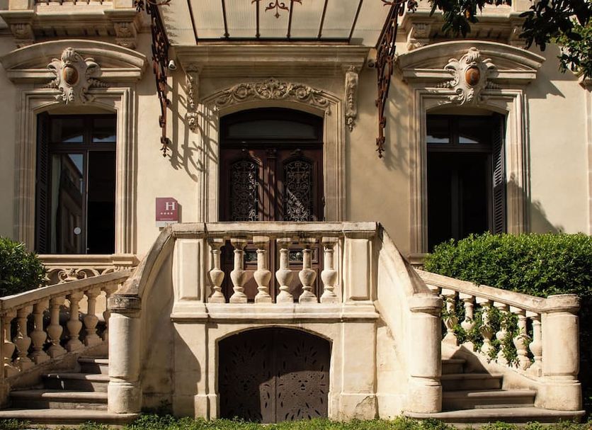 L'Hôtel Particulier Beziers exterior with ornate stone staircase and historic facade in Béziers