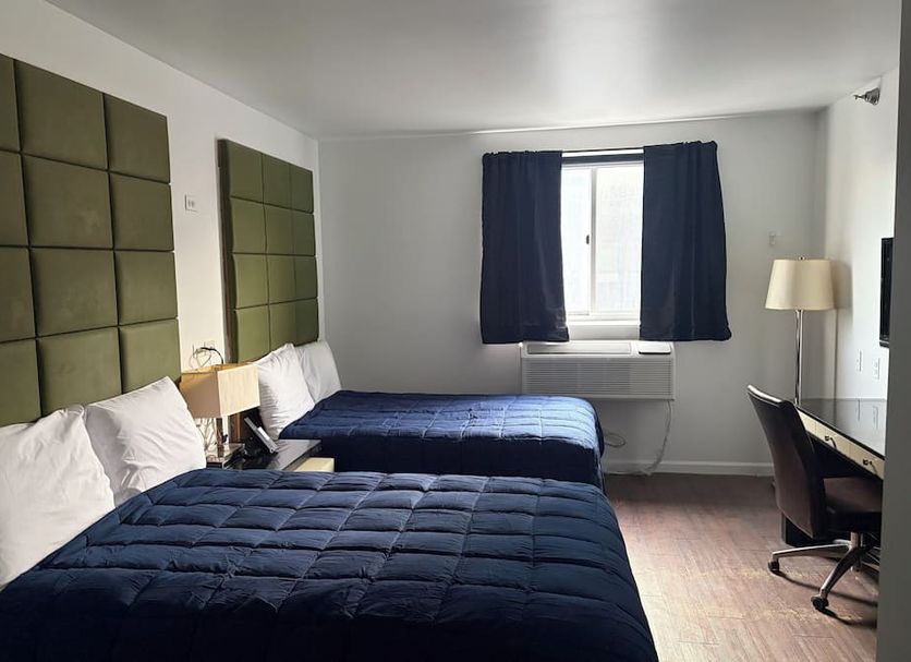 Hotel Bpm Brooklyn room in Brooklyn with two beds, navy bedding, desk, and window with dark curtains