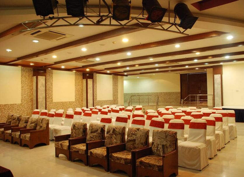 Hotel Ganga Ratan in Agra conference hall with rows of white chairs and a stage