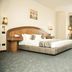Cherry Maryski Hotel in Alexandria guest room with king bed, desk, chairs, and carpeted floor