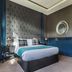 The Coal Exchange Hotel Cardiff guest room with tufted headboard, blue paneling and patterned wallpaper
