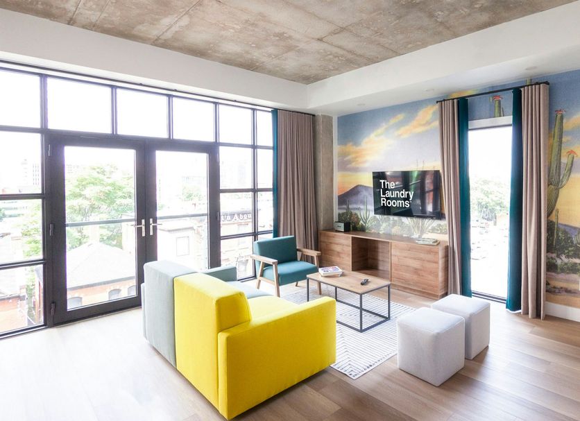 The Laundry Rooms Augusta Hamilton in Hamilton: bright suite with mural wall, sofa, TV, and balcony view