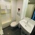Hotel De La Paix Interlaken bathroom with wall-mounted toilet, sink, mirror, shower, and towel shelf