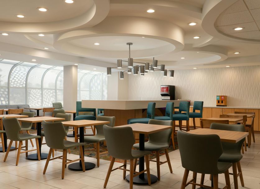 Hampton Inn by Hilton Hopewell Fort Lee breakfast area with tables, chairs, and a modern ceiling design