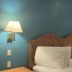 Motel 6 Portland, IN guest room with wooden headboard, twin beds, wall lamps and blue walls