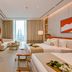 Onyx Rotana in Manama, bright suite with twin beds, sitting area and sea view through floor-to-ceiling windows