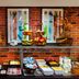 Leonardo Boutique Hotel Krakow Old Town breakfast buffet with fruit, pastries, and cold items against a brick wall.