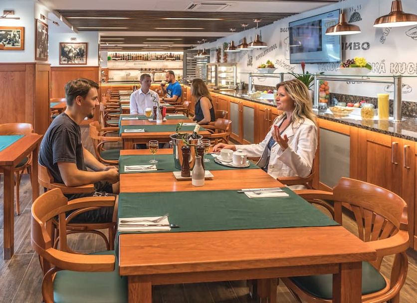Wellness Hotel Step Prague restaurant with guests seated at wooden tables and buffet counter