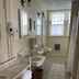 Moseley Cottage Inn and The Town Motel bathroom with double sinks, wicker towel rack, and patterned rugs in Bar Harbor